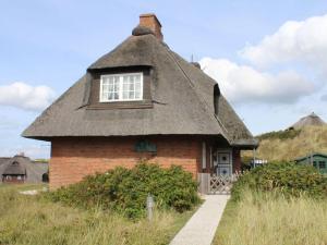 a small brick house with a thatched roof at Haus Hoppel - FeWo ground floor in Rantum