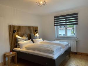 een slaapkamer met een bed met witte lakens en een raam bij Schleichhof Ammersee in Dießen am Ammersee
