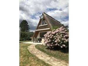una casa con techo de paja y un arbusto de flores rosas en Finnhütte lake view, 