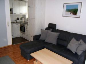 ein Wohnzimmer mit einem schwarzen Sofa und einer Küche in der Unterkunft "At Low 8" Merchant in Horumersiel
