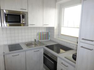 eine weiße Küche mit einer Spüle und einer Mikrowelle in der Unterkunft "At Low 8" Merchant in Horumersiel