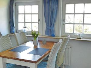 una mesa de comedor y sillas con cortinas azules en Haus Ruusenhoog - Apartment 5, en Rantum