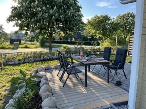 una terrazza in legno con tavolo e sedie. di The Nordseehus Modern retreat a Dagebüll