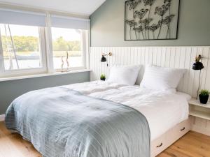 - une chambre avec un grand lit blanc et une fenêtre dans l'établissement Oceanhouse Modern Retreat, à Den Oever