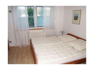 ein weißes Bett in einem Schlafzimmer mit einem Fenster in der Unterkunft Heinrich Tiarksstrasse 36 in Horumersiel