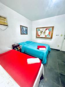 una camera con due letti e un divano rosso di Recanto Natural - Rock In Rio All Inclusive a Rio de Janeiro