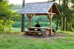 a man sitting on a bench with a solar roof at Kempings Ozolkalns in Cēsis
