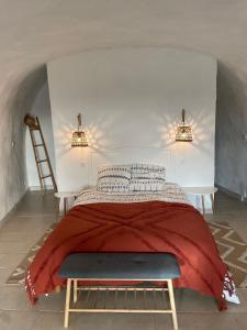 een slaapkamer met een bed met een rode deken bij Logement troglodyte tout confort 42 min tgv Paris in Naveil