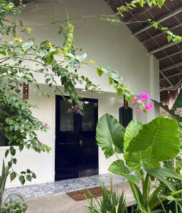 a house with a black door and some plants at 11th Earth Farm and Resort in Nabua