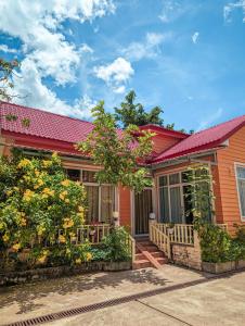 a house with a red roof and some plants at Yellow Star Hostel in Kampot