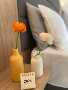 twee vazen met bloemen op een tafel naast een bed bij Hotel Londra in Milano Marittima