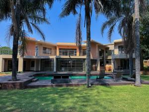 a house with a swimming pool and palm trees at Fullbliss Guesthouse in Johannesburg