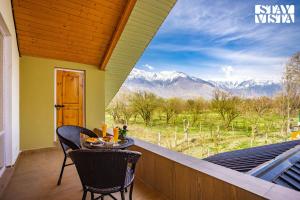 a table and chairs on a balcony with a view of mountains at The Dewan Bagh with Heater at Srinagar by StayVista in Srinagar