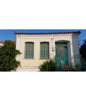 een huis met een groene deur en ramen bij Traditional Stone House in Koustáros