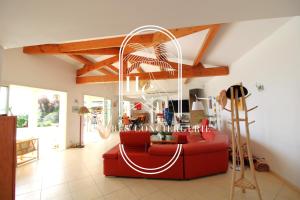 Somptueuse Villa l'Oasis By HC في كاركيران: غرفة معيشة بها أريكة حمراء وثريا