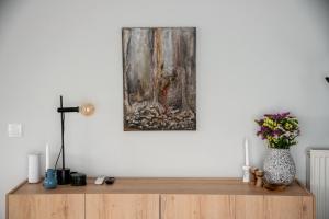 un dipinto appeso a un muro sopra un comò di legno di eugea apartments a Città di Lefkada