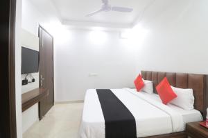 1 dormitorio con 1 cama con almohadas rojas y TV en Hotel Golden Prime en Nueva Delhi