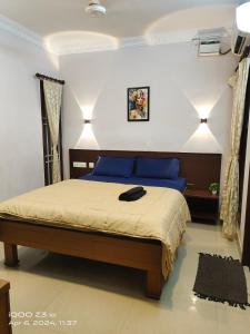 a bedroom with a large bed with blue pillows at Nest Inn in Puducherry