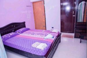 ein Schlafzimmer mit einem lila Bett und einer Holztür in der Unterkunft BRUNDHA HOMESTAY Villa with Garden in Tirupati