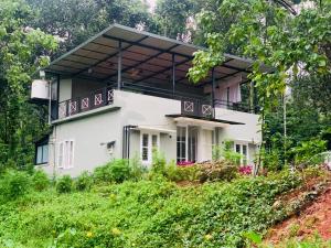 a house with a balcony on top of a hill at Vythiriii county side homestay in Vythiri