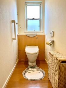 a bathroom with a toilet with a window and a rug at Guest room Kurume in Miimachi
