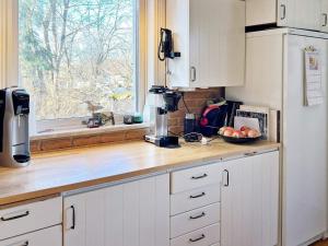 una cocina con armarios blancos y una encimera con ventana en Holiday home EKERÖ, en Ekerö