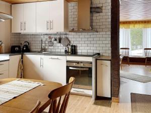 uma cozinha com armários brancos, uma mesa e uma sala de jantar em Holiday home GRISSLEHAMN XV em Grisslehamn
