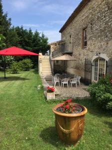 a yard with a large pot with flowers in front of a building at Gîte Le Mas du Colombeyras in Espeluche