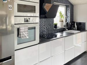 Holiday home Ronneby XIV في رونيبي: مطبخ مع دواليب بيضاء ومغسلة