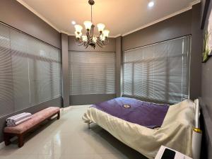 a bedroom with a bed and a chandelier and windows at Villa88 in San Kamphaeng
