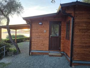 a small wooden cabin with a door and a tree at Campeggio Gianna Golfo dei Poeti in Lerici