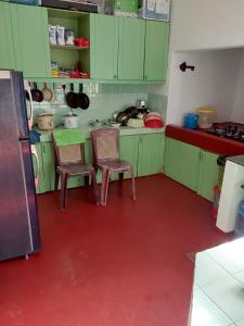 cocina verde con 2 sillas y mesa en Kandy Breeze Stay, en Urulewatta