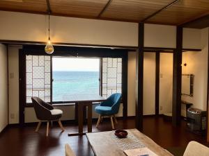 a dining room with a table and chairs and a window at Uminone in Toyooka