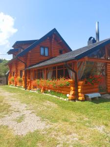 a log cabin with flowers in front of it at Cabana Razesilor in Gura Humorului