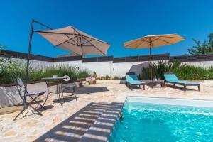 a swimming pool with two umbrellas and a table and chairs at Kuća za odmor Laurus s bazenom in Kukljica
