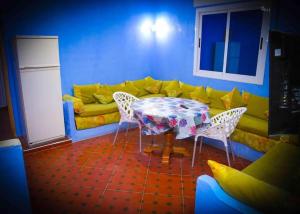 uma sala de estar com uma mesa e um sofá amarelo em Silius em Chefchaouen