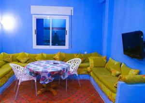 uma sala de estar com um sofá amarelo e uma mesa em Silius em Chefchaouen