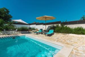 a swimming pool with two chairs and an umbrella at Kuća za odmor Laurus s bazenom in Kukljica