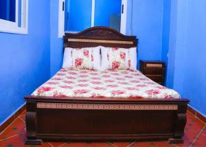uma cama num quarto azul com uma colcha vermelha e branca em Silius em Chefchaouen
