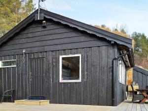 Un granero negro con una ventana en el costado. en 4 person holiday home in ydegard, en Torvikbukt