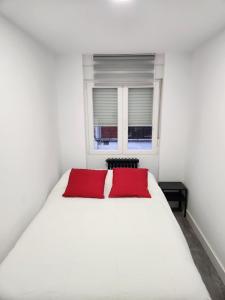 a bedroom with a white bed with two red pillows at Piso centrico, Cerca de los hospitales y centro. in León