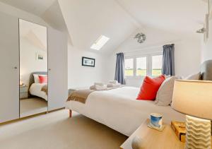 1 dormitorio con 1 cama blanca grande y espejo en Saffron Cottage, en Saint Ervan