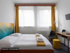 a bedroom with a bed with a desk and a window at Hotel AMITY in Prague
