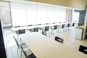 Osaka City Hotel Kyobashi في أوساكا: قاعة اجتماعات مع طاولات وكراسي بيضاء