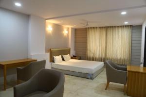 een slaapkamer met een bed en een bank en stoelen bij A Luxury Stay in S9 Hotel and Restaurant Near Ambaji in Ambaji