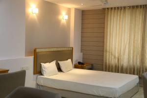 een slaapkamer met een bed met witte lakens en witte kussens bij A Luxury Stay in S9 Hotel and Restaurant Near Ambaji in Ambaji