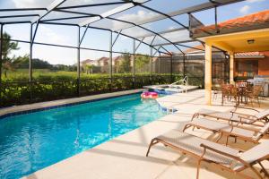 a swimming pool with chairs and a house with a swimming pool at Solterra Resort 5 Bedroom Vacation Home with Pool 1604 in Davenport
