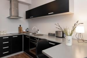 a kitchen with black cabinets and a table with a vase of flowers at Jaamamõisa apartement in Tartu