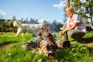 a woman and a dog playing around a campfire at Kempings Ozolkalns in Cēsis