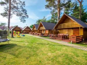 a row of wooden lodges with a playground in the yard at Holiday house for 5 people, Jaros awiec in Jarosławiec